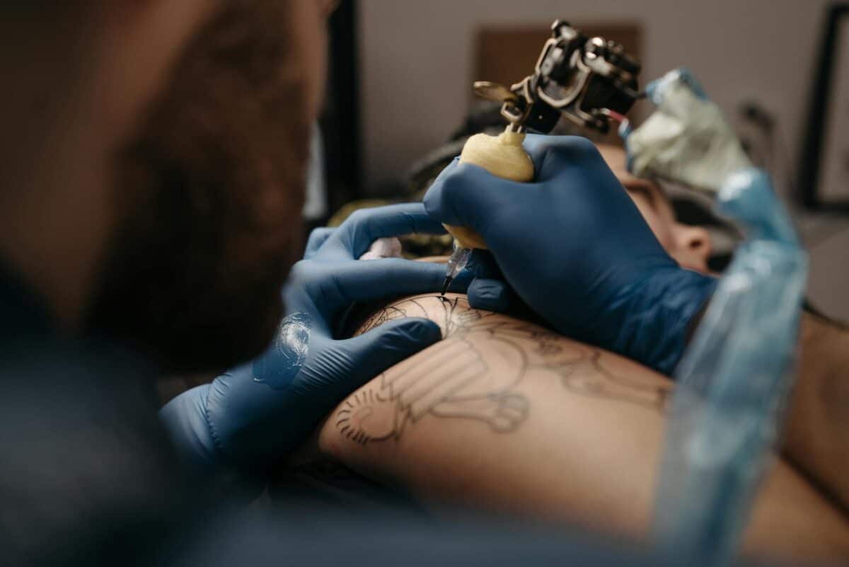 A Tattoo Artist working with a bagged machine and wrapped cord