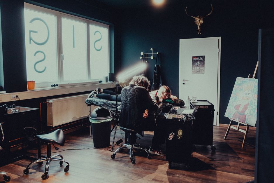 Tattoo artist working on a client in a modern studio in Keltern, Germany. The ambiance is creative and professional.