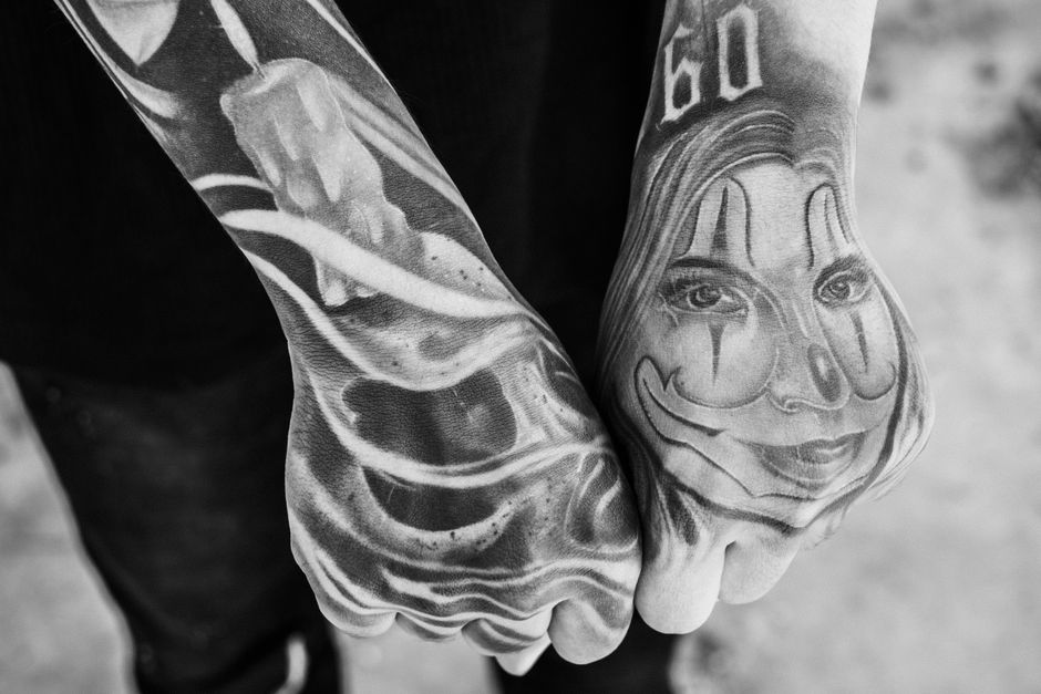 Black and white of crop anonymous cool person demonstrating tattoos of woman and burning candle in daytime